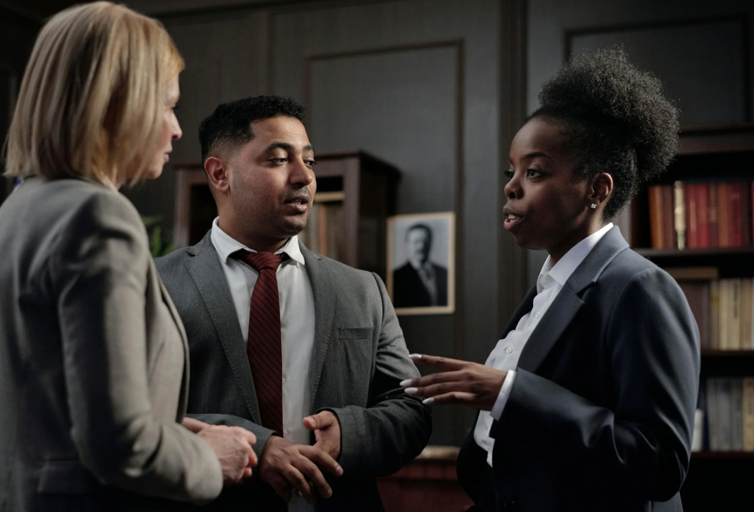 Three business professionals engaged in a discussion in an office setting.