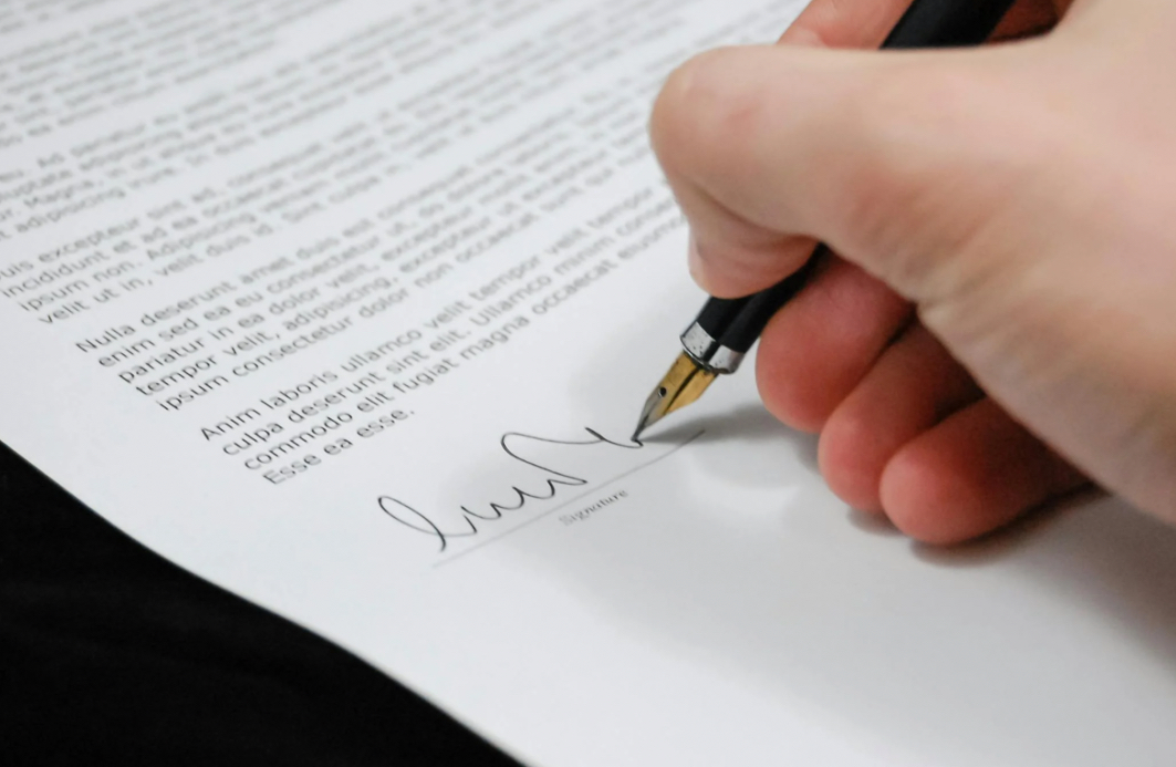 Person signing a document with a fountain pen.