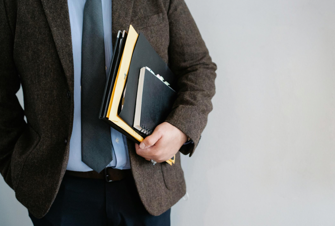 Close-up of a person holding notebooks and folders.