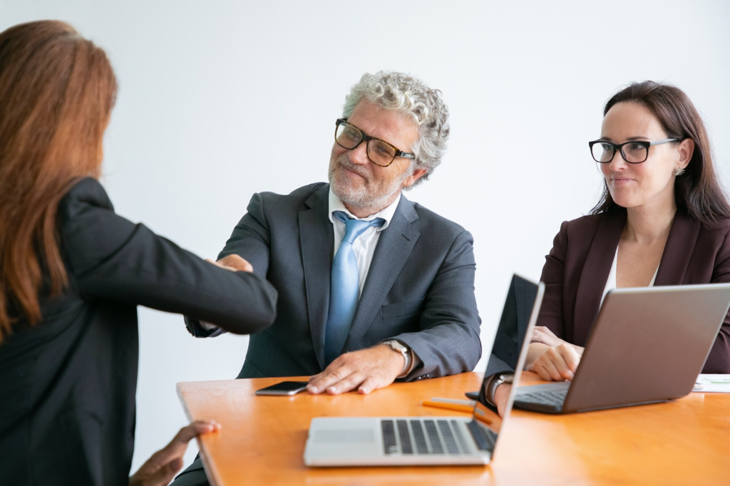 Businesswoman greeting bearded colleague